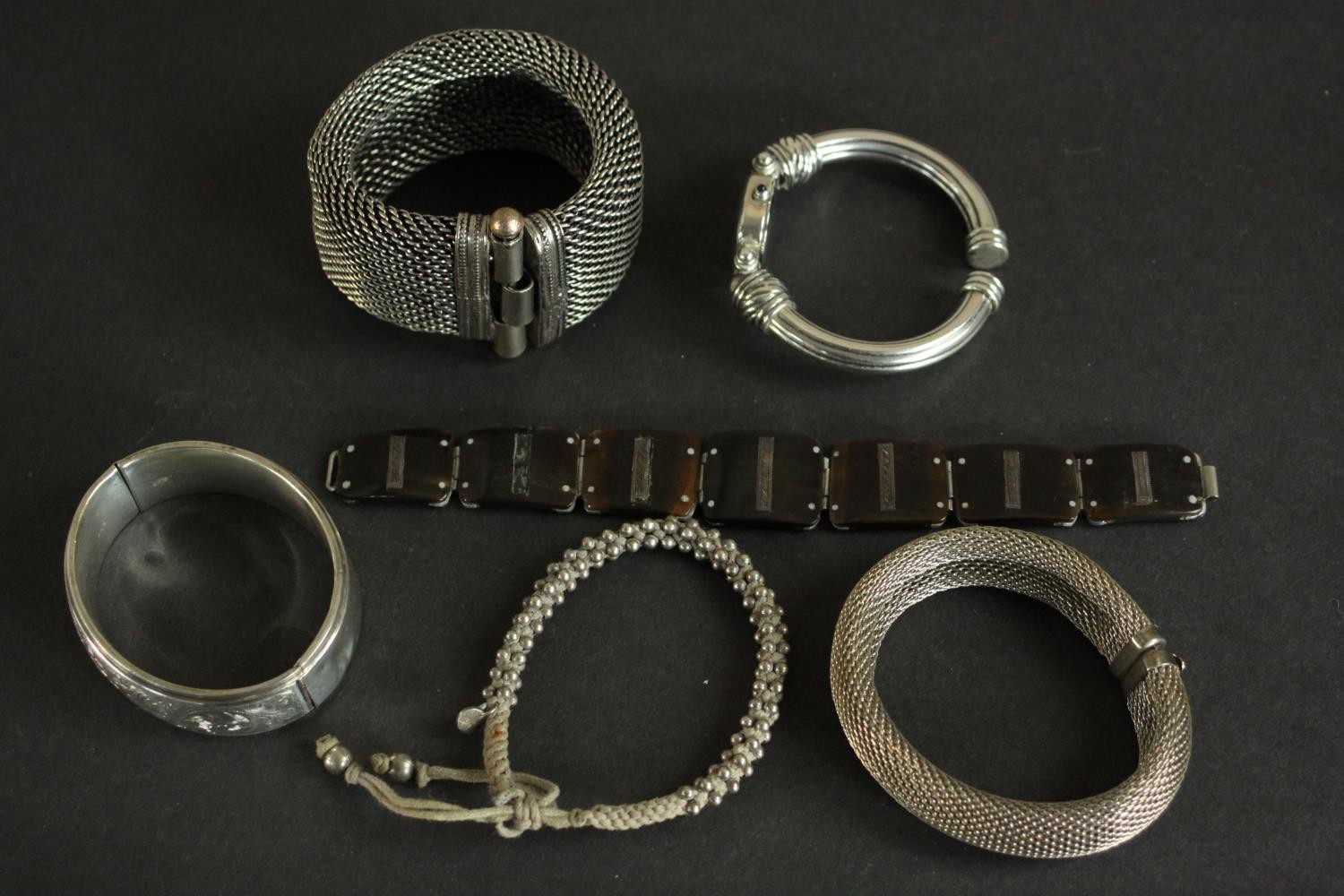 A collection of silver bangles, a silver bangle watch and a tortoiseshell and silver articulated