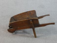 A pine child's size wheelbarrow, with two pine handles and a pine wheel with an iron rim. H.38 W.