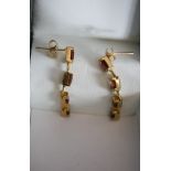 A pair of 9ct yellow gold and orange stone articulated earrings. Each earing set with four