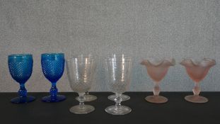 A pair of frosted peach glass ice cream glasses along with a pair of pressed blue glass wine goblets