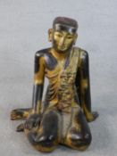 An early 20th century South East Asian carved figure of a monk, depicted seated with robes draped