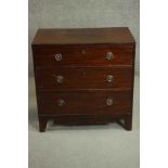 A George III mahogany chest of three long drawers with brass ring handles over a shaped apron and