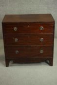 A George III mahogany chest of three long drawers with brass ring handles over a shaped apron and