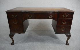 An Edwardian mahogany writing table, the top with a tooled brown leather writing surface and a bow