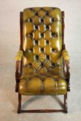 A mahogany slipper chair upholstered in green buttoned leather with studded edges, the legs joined