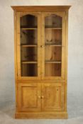 A late 20th century pine bookcase with a pair of glazed doors enclosing shelves over a pair of