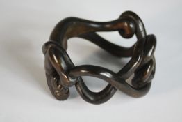 An early 20th century carved and pierced hardwood bangle in the form of a mystical creature