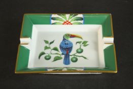 A Hermes porcelain ashtray, with a green and gilt border, centred by a toucan on a branch. H.4 W.