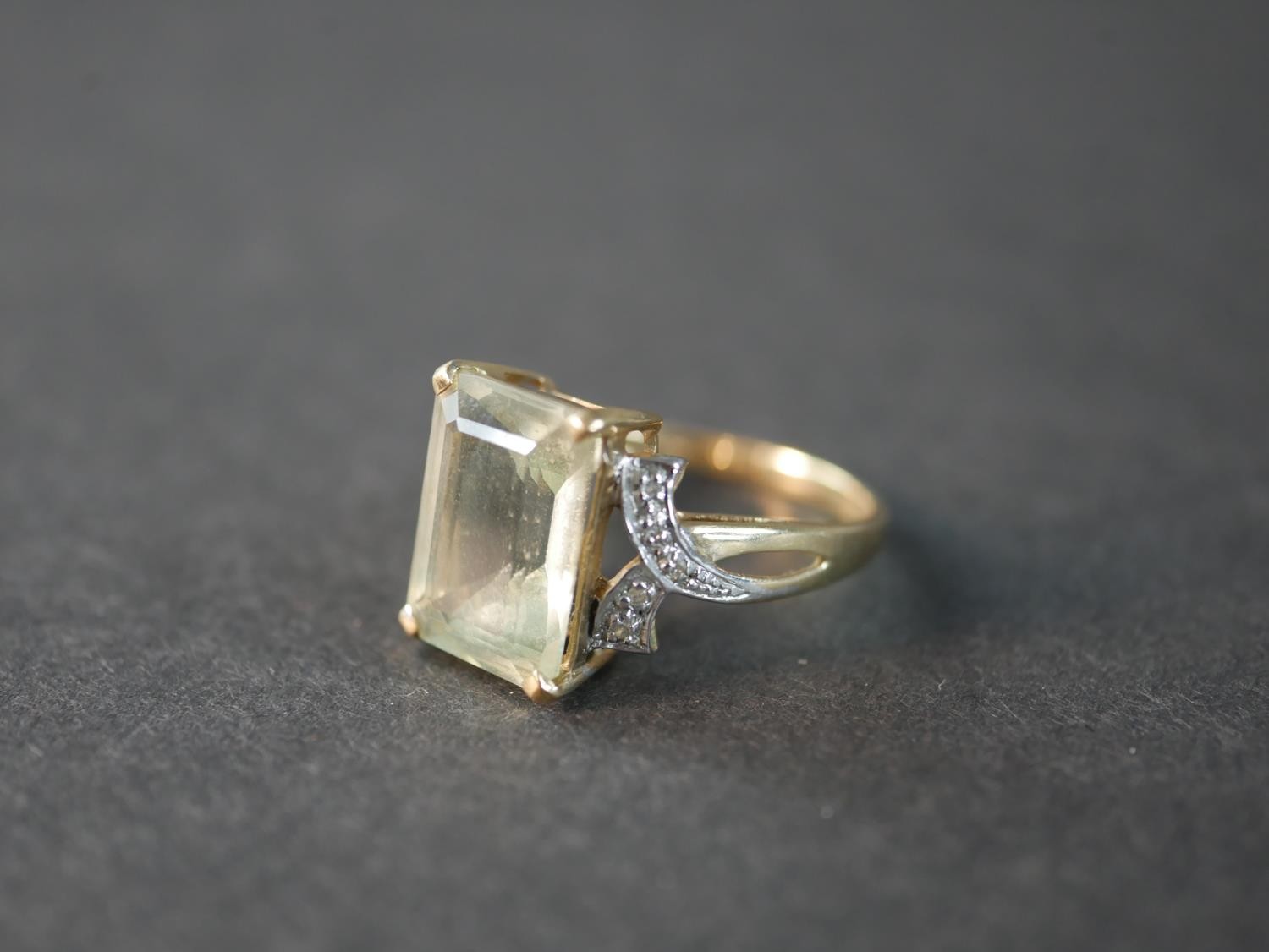 A 9 carat topaz and diamond dress ring, set to centre with a rectangular emerald cut topaz with an