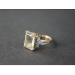 A 9 carat topaz and diamond dress ring, set to centre with a rectangular emerald cut topaz with an