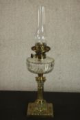 A Victorian brass repousse classical column design oil lamp with cut glass well. H.64 W.15cm.