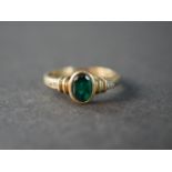 A 9 carat gold emerald paste and diamond flanked solitaire ring, set with four round eight cut