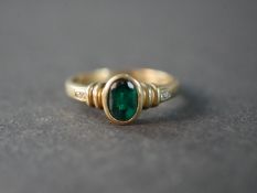 A 9 carat gold emerald paste and diamond flanked solitaire ring, set with four round eight cut