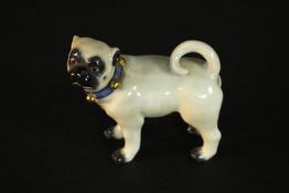 A Meissen porcelain figure of a pug dog, standing with a curled tail and looking to its left,