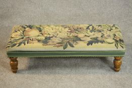 A tapestry upholstered long footstool, on turned fruitwood legs. H.23 W.82 D.38cm.