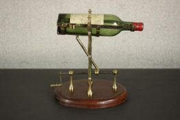 A mechanical brass wine pourer with a crank handle on an oval mahogany base. H.34 W.30 D.22cm.