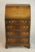 A George III style mahogany bureau, the fall front enclosing a drawer and pigeonholes, over four