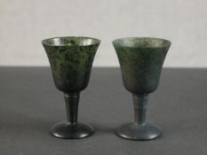 A pair of Chinese spinach jade miniature goblets with bell shaped bowls, tapered stems and domed