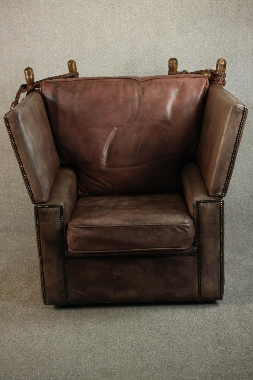 A Knole style contemporary brown leather armchair, with turned stained beech finials and studded