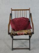 An early 20th century fruitwood folding armchair, with a spindle back, the seat upholstered in a