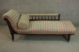A late Victorian walnut chaise longue, upholstered in chequered fabric, with a bolster cushion,