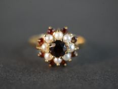 A 9 carat pearl and garnet cluster ring, set with nine round mixed cut garnets with a combined