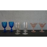 A pair of frosted peach glass ice cream glasses along with a pair of pressed blue glass wine goblets