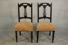 A pair of late Victorian walnut dining chairs, with pierced splat backs over yellow upholstered