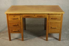 A circa 1940s oak utility furniture style desk, with a rectangular top over two slides and an