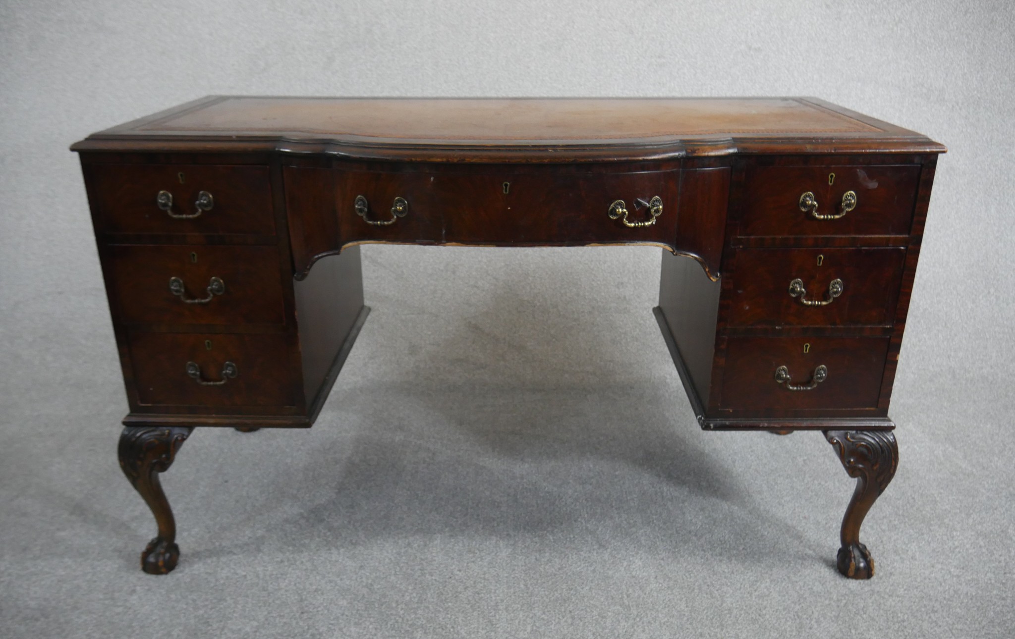 An Edwardian mahogany writing table, the top with a tooled brown leather writing surface and a bow