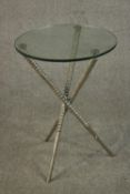 A contemporary occasional table, with a circular glass top on a based formed of three crossed
