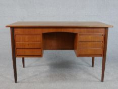 A circa 1960s teak kneehole desk, the rectangular top over two banks of three drawers on tapering