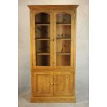 A late 20th century pine bookcase with a pair of glazed doors enclosing shelves over a pair of