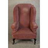A 19th century wingback armchair, upholstered in pink velour with scrolling arms, on ebonised