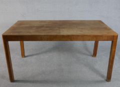 An Art Deco figured walnut dining table, the quarter veneered rectangular top supported by legs with