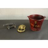 A large brass lion head door knocker along with a painted iron bucket with a coca cola design and an