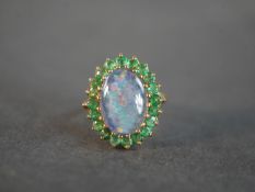 A 9 carat yellow gold black opal triplet and emerald cluster dress ring. Set to the centre with an