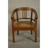 An early 20th century teak tub chair, with a caned seat and raised on square section legs.