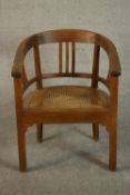 An early 20th century teak tub chair, with a caned seat and raised on square section legs.