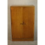 A mid 20th century Meredew oak Linen press, the two doors enclosing linen slide, on a plinth base,