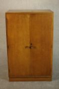 A mid 20th century Meredew oak Linen press, the two doors enclosing linen slide, on a plinth base,