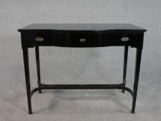 A contemporary ebonised bow front side table, with three short drawers on square section tapering