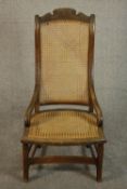 A circa 1900 hardwood nursing chair, with a caned seat and back, the legs joined by stretchers.