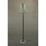 A 20th century brass standard lamp, with a cast tri-form base on a circular white marble plinth,