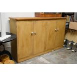 A vintage distressed painted pine housekeepers cabinet with panel doors enclosing shelves on a