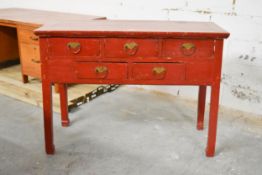 A C.1900 Chinese red lacquered side table fitted with an arrangement of drawers on square section
