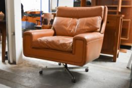 A 1970s vintage light tan leather upholstered armchair with swivel and reclining action on a four