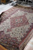 A large Persian style carpet with central medallion on a biscuit ground with floral decoration