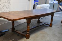 A 17th century style oak refectory dining table with planked and cleated top and twin extension