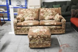 A two seater floral upholstered sofa and matching footstool. H.75 x W.165cm